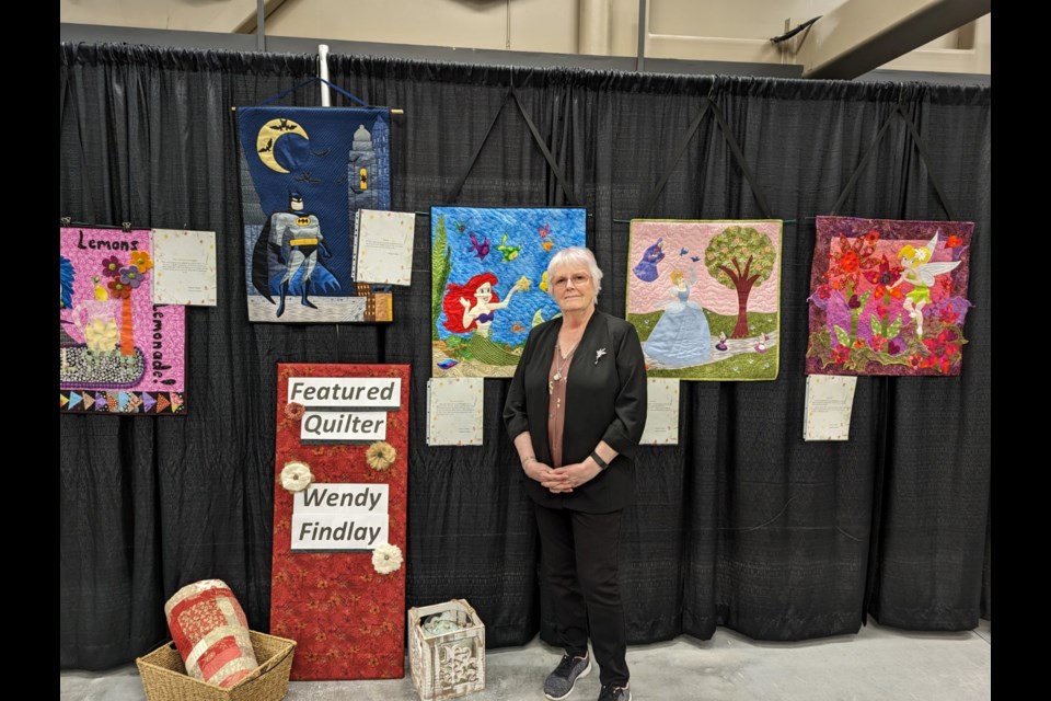 Featured Quilter Wendy Findlay stands with a sample of the work she had on display