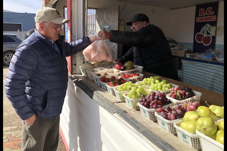 A customer accepts his package from Todd Bell (right), owner of B&B Fruit Stand, during the kiosk's first day open for the 2024 season. Photo by Jason G. Antonio 