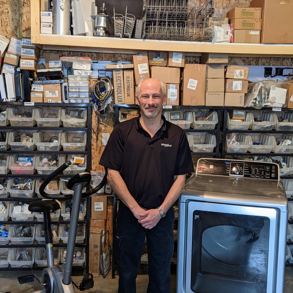 Doug Moffatt stands in front of a wall of parts