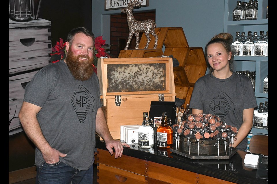 Honey Pot Distillery proprietors Cory and Stacey Martin next to their actual, living beehive in their restaurant.