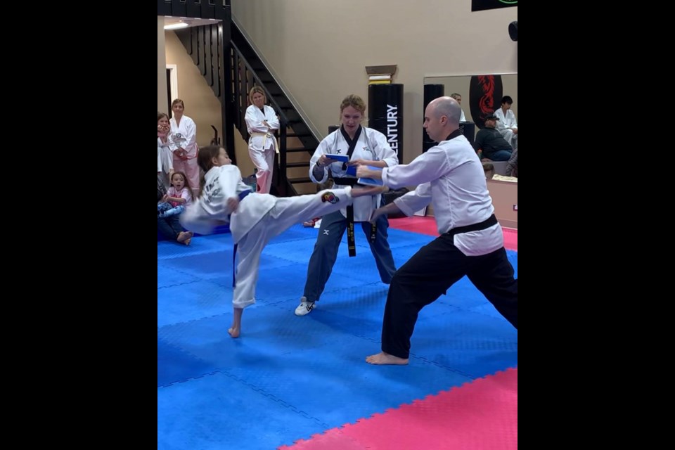 Instructor Nathan Douglas, far right, holds a board for a board-breaking student
