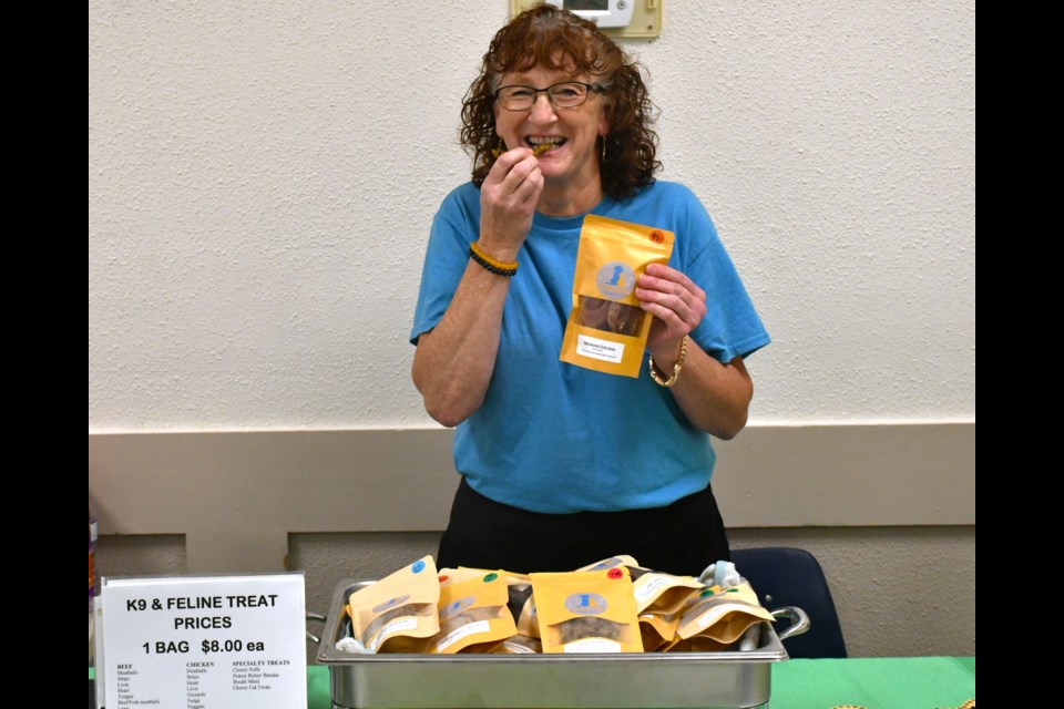 Diane Loos of K9 & Feline Treats and Things samples one of her homemade dog treats during the Shriners marketplace — proving confidence in her brand.