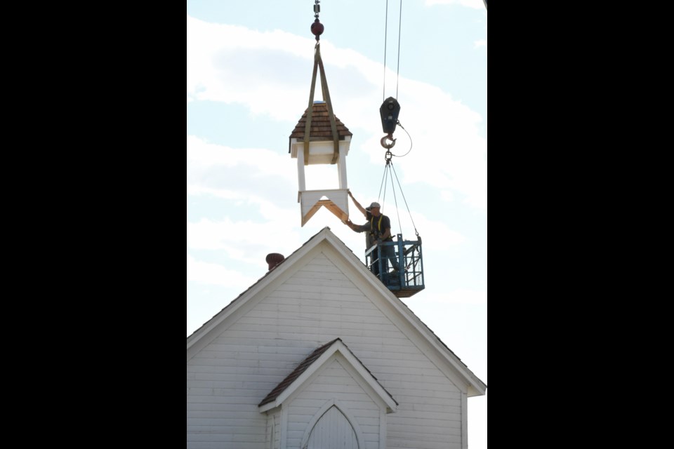 Volunteers Dave Delahey and Dan Goud guide the bell tower into place. Photo by Jason G. Antonio