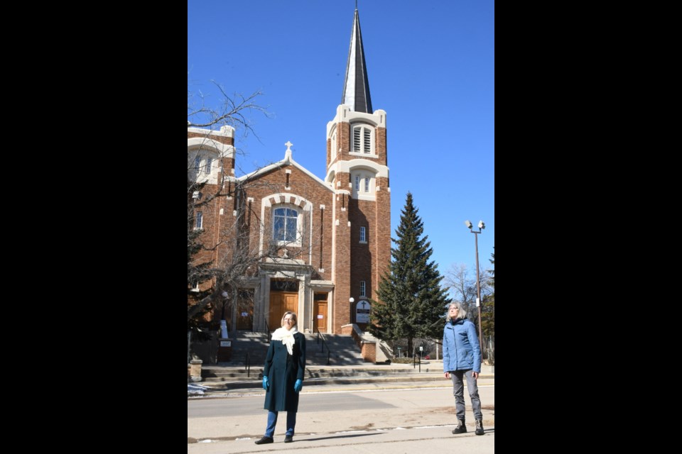 Janie Fries and Rosalie Boots stand outside St. Joseph Roman Catholic Church in April 2020 and listen to the bells ring out, as part of a new initiative to offer hope to the community during the pandemic. The parish will ring the bells again from March 8 to 12 to mark the first anniversary of the pandemic. Photo by Jason G. Antonio 