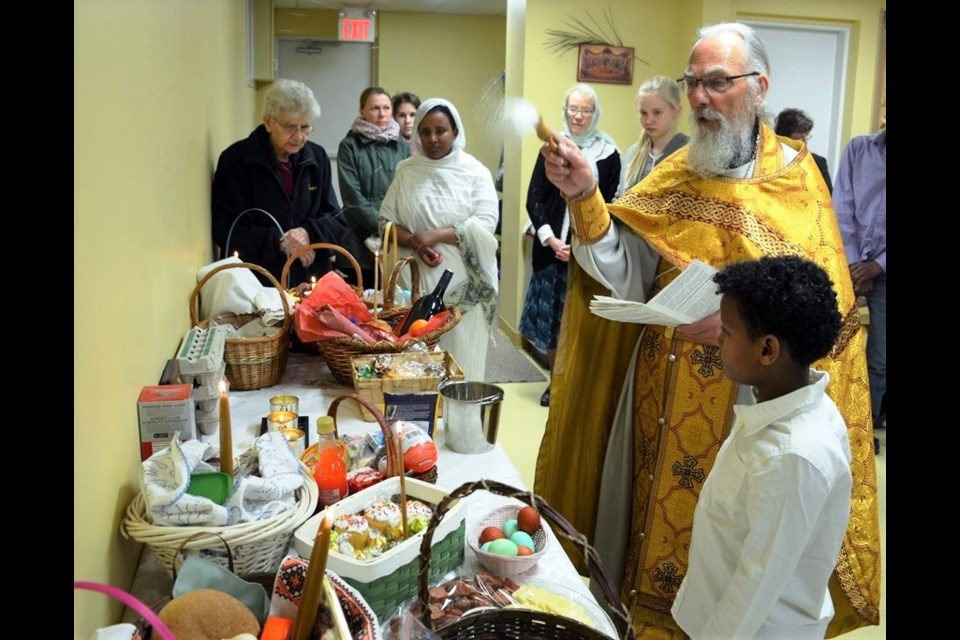 With help from a young parishioner, Father John Bingham blesses a midnight lunch after Easter services in 2017. Photo courtesy Holy Trinity Orthodox Church