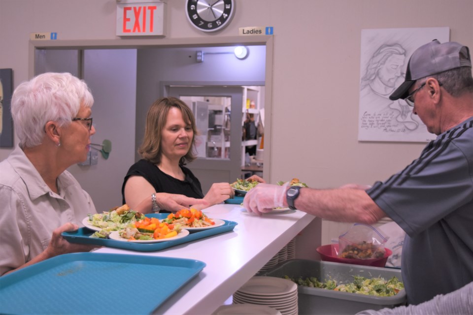 Volunteers Judy Rysavy, Lynn Froehlich and Harvey Parker prepare to bring salads to clients’ tables during the start of Riverside Mission’s Easter supper on April 18. Photo by Jason G. Antonio