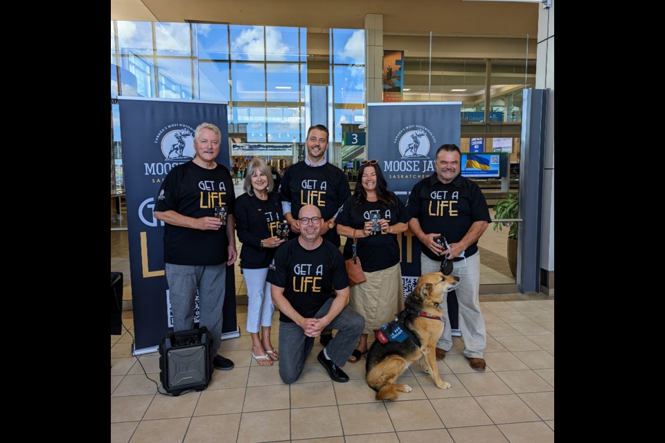 (l-r) Moose Jaw Mayor Clive Tolley, Regina Airport Authority board chair Trish Martynook, city communications manager Craig Hemingway (kneeling), Moose Jaw North MLA Tim McLeod, founder and CEO of MemoryKPR Jessica McNaughton, Moose Jaw Wakamow MLA Greg Lawrence, and Oliver (Lawrence's service dog)