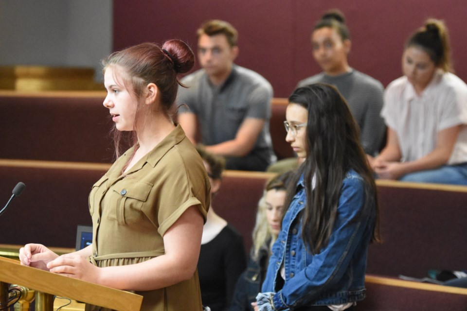 Meagan Barclay (left), a student at Cornerstone Christian School and member of the municipal youth advisory committee, speaks to city council about why BioBags are better alternatives than plastic bags. The rest of the committee members sit behind her in the gallery. Photo by Jason G. Antonio