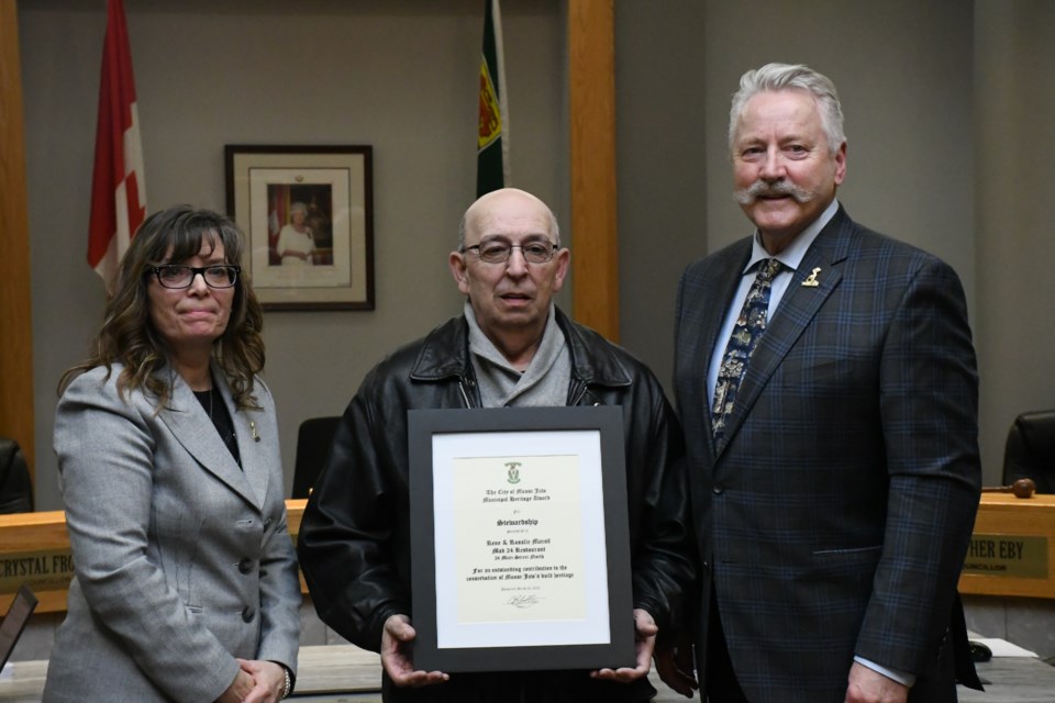 Coun. Crystal Froese (left) and Mayor Clive Tolley present a plaque to the building owner of MAD 24 Restaurant (formerly National Cafe) as part of the 2022 municipal heritage awards program. Photo by Jason G. Antonio