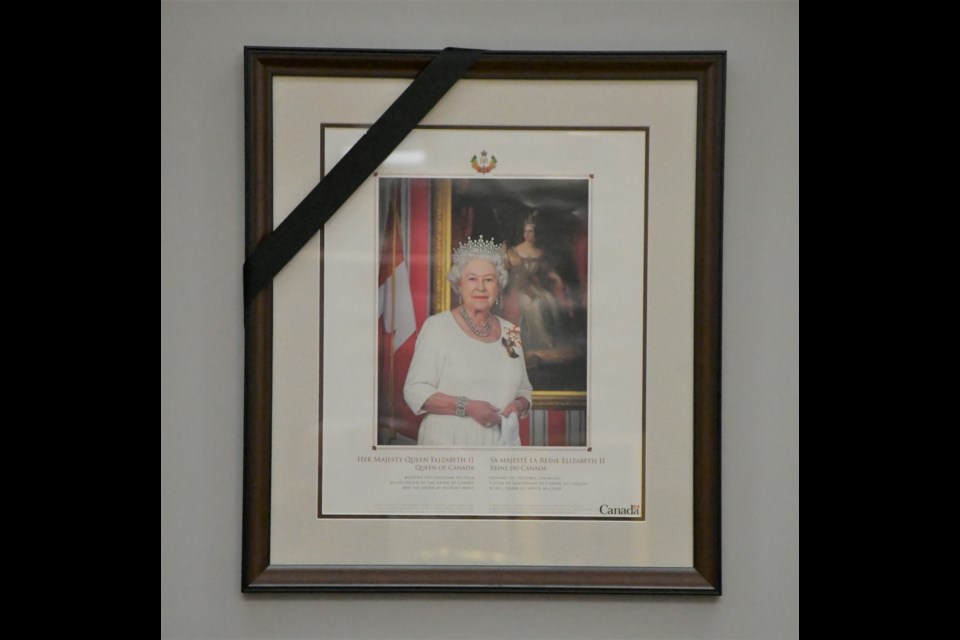 A black ribbon adorns a picture frame of Queen Elizabeth II in council chamber to commemorate her death. Photo by Jason G. Antonio 