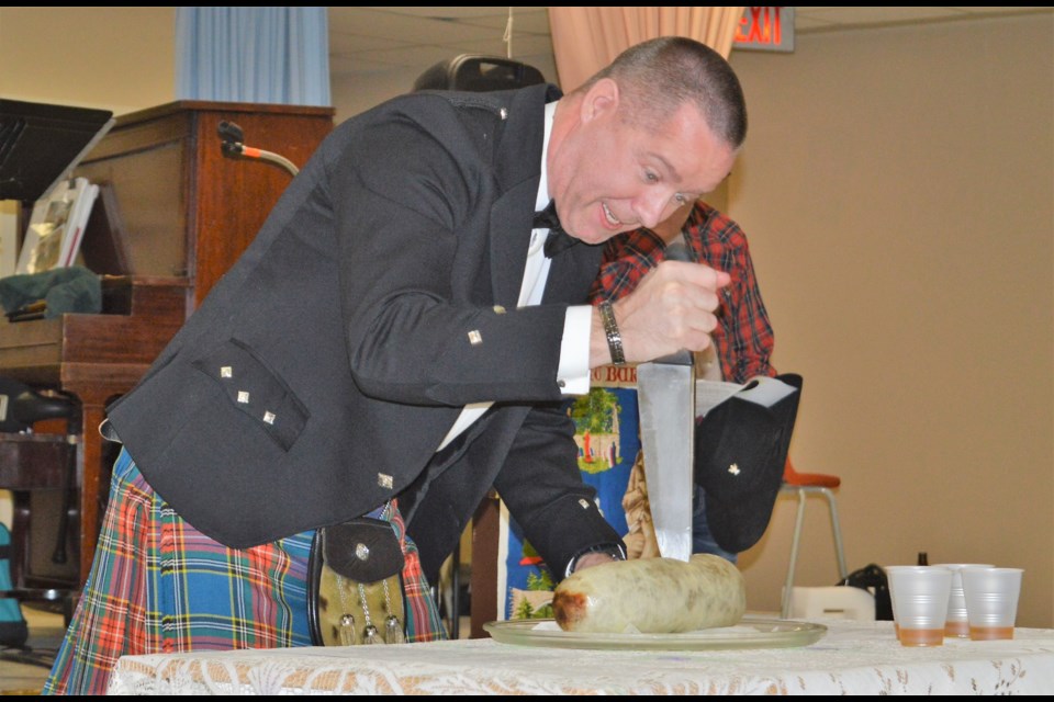Andrew Gallagher stabs the haggis with a dagger during the "Address to the Haggis" at the Burns Night celebration at Timothy Eaton's. (Matthew Gourlie photograph)