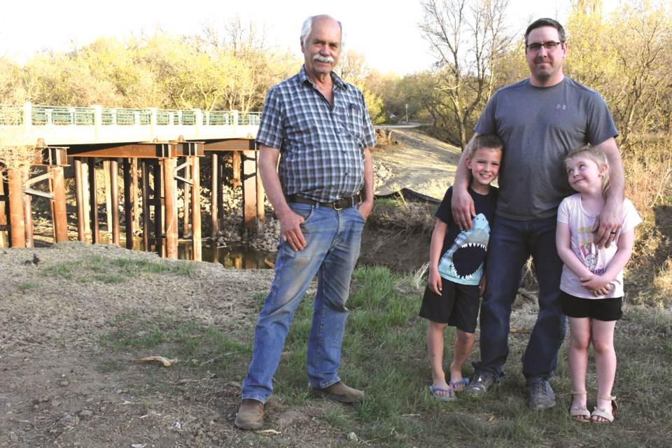 Jim Thorn (left) and Tim Avery, with Evan and T.J., pose near the Seventh Avenue Southwest bridge on May 13. The families are relieved that the bridge is open so they can travel for work and school easier. Photo by Jason G. Antonio 
