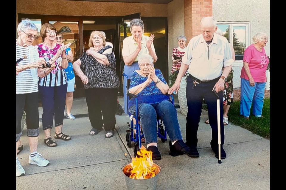 Co-op members gather to watch a copy of the mortgage being symbolically burned. The Rosewood Housing Co-operative is now fully owned by its residents. The occasion featured original members Shirley (in wheelchair) and Don Stockton (with cane).