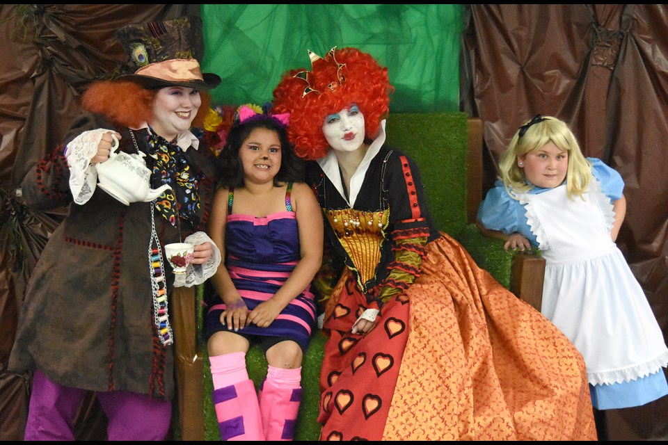 The Mad Hatter, Queen of Hearts and Alice come together for a photo with a youngster in the Alice in Wonderland room.