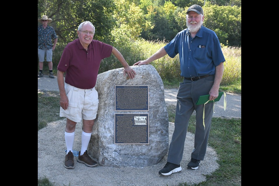 Rick Evans and Don Mitchell with the monument describing the Evans Florist Greenhouse and Churchill Park Greenhouse Co-op  in Churchill Park.