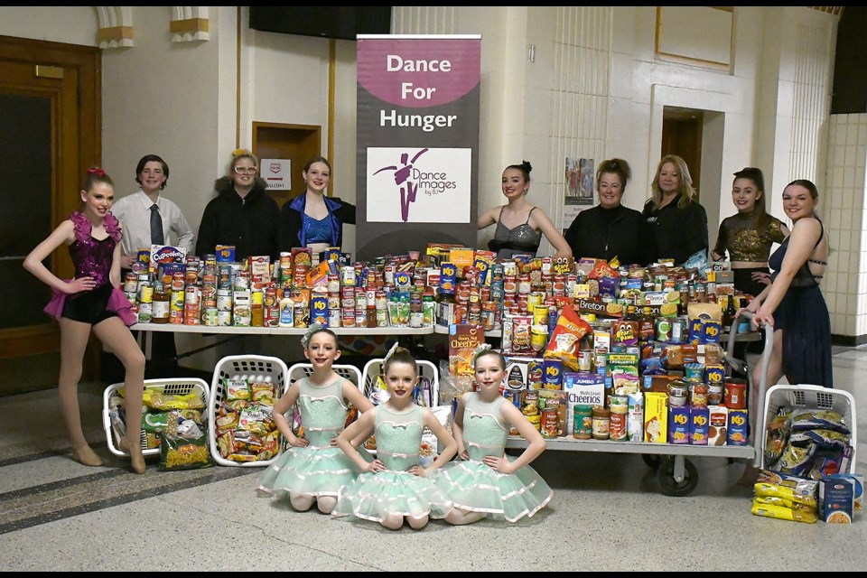 Performers with Dance Images by BJ join members of the Moose Jaw and District Food Bank for a photo of the huge pile of donations from Dance for Hunger.