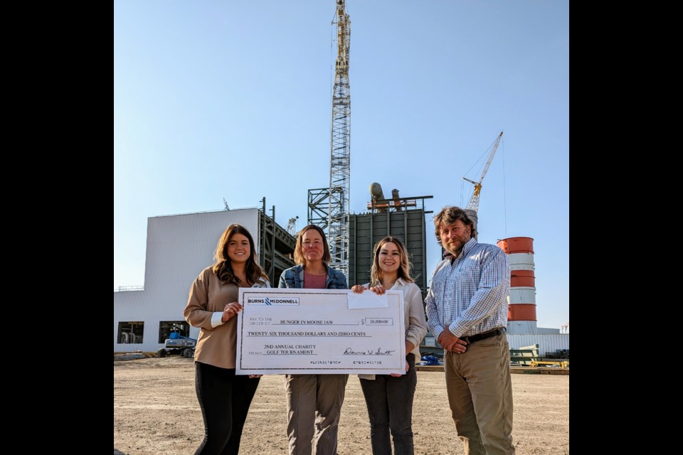 (l-r) Jami-Lee Cuthbert, Sharla Sept, Jade Wilcox, and Brad Butcher stand in front of the rapidly-ascending Great Plains Power Station