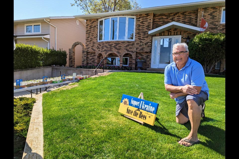 Len Mintenko at his home with a sign he made for the occasion, and sunflowers for sale in his driveway