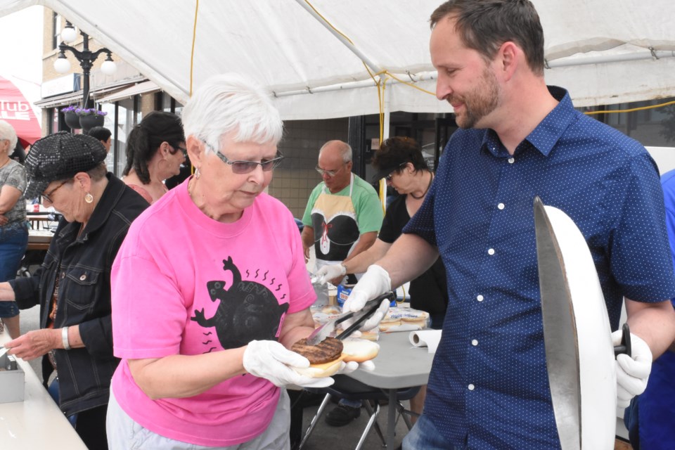 Saskatchewan NDP leader Ryan Meili (right) serves up hamburgers at the Timothy Eaton Centre on July 5 during Sidewalk Days with other volunteers such as Barbara Yates. Meili met with staff from Palliser Regional Library to hear their concerns about provincial funding. Photo by Jason G. Antonio 