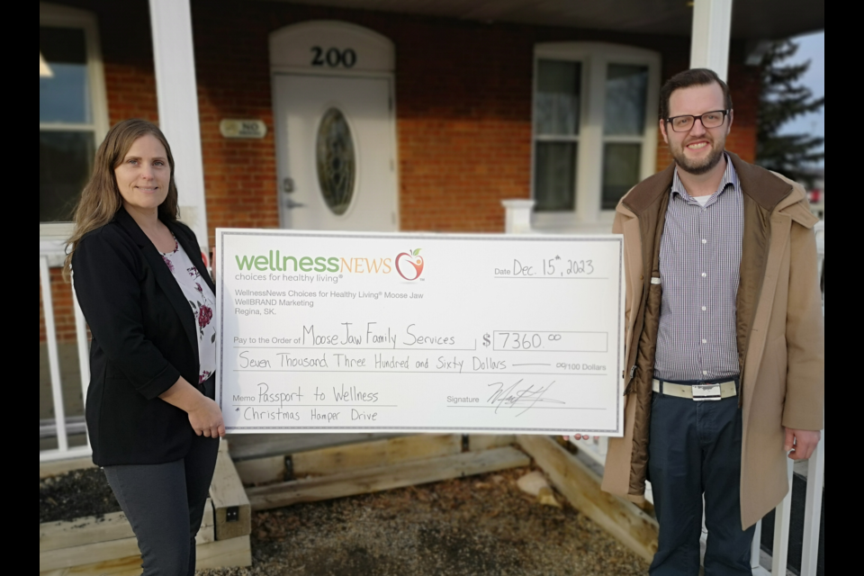 Tara Jones (left) receives a cheque on behalf of Moose Jaw Family Services, presented by Mark Tustin (right) with WellnessNews.