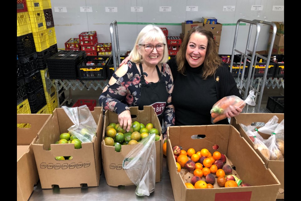 Volunteer Karen Dolan and Deann Little, development, volunteer and warehouse manager at the food bank, sort through fruits. Photo by Jason G. Antonio