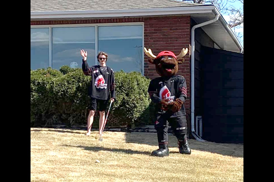 Moose Jaw Warriors defenceman Nolan Jones waves at Moose Jaw Birthday Parade participants during his 19th birthday celebration alongside none other than Morty.