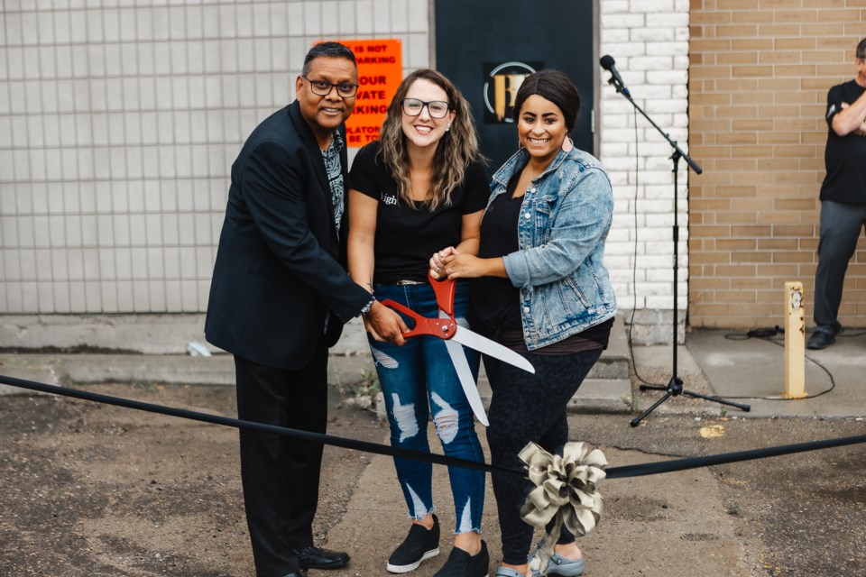 Larry Hasmatali, pastor of the Moose Jaw Church of God, joins co-directors Kyleigh Coad and Jessika Kopp in cutting the ribbon