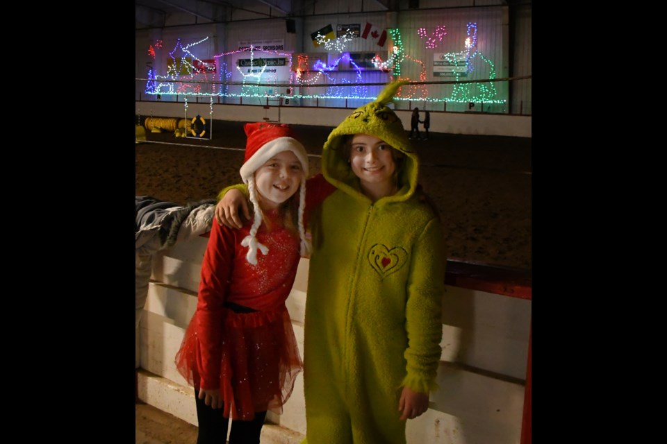 Riata Elford and Sierra Good with the Moose Jaw Over the Top Vaulters pause for a photo as the Christmas at the Ex Nativity light show plays in the background.