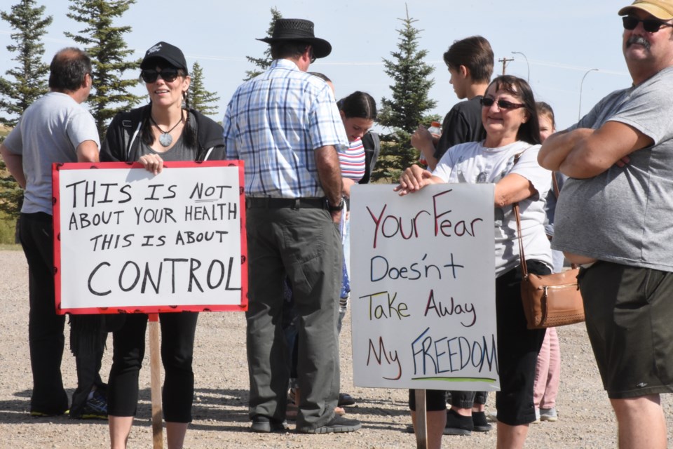 Some of the 70 people who attended the anti-mask rally brought signs expressing their opinions. Photo by Jason G. Antonio 