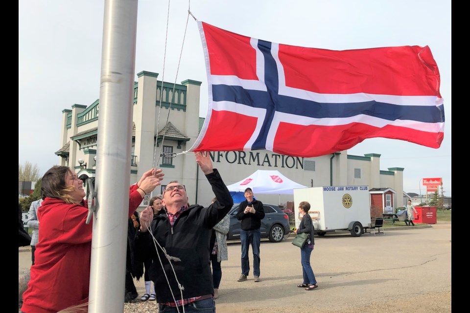 Jacki L’Heureux-Mason, executive director for Tourism Moose Jaw, and Mayor Fraser Tolmie raise the Norwegian flag outside of the tourism centre on May 17 during the inaugural Norway Day. Photo by Jason G. Antonio 