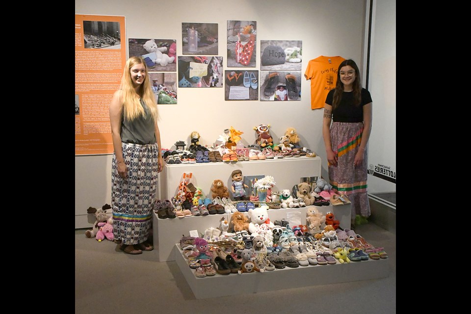 Cassidy and Kayleigh Olson pause for a photo with some of the 500 pairs of shoes that were placed on the steps of St. Andrew’s United Church and are now part of the Indigenous display in the Moose Jaw Museum and Art Gallery.