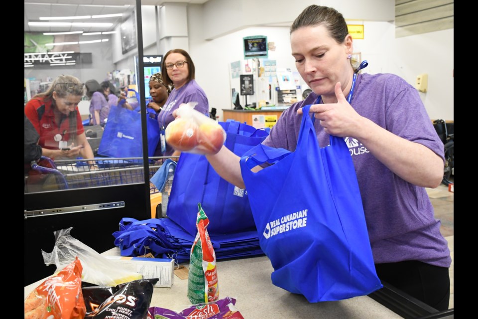 Jennifer Angus, executive director of Transition House, helps bag groceries at the Co-op food store, during the kickoff of the Project Shine fundraiser for May. Photo by Jason G. Antonio