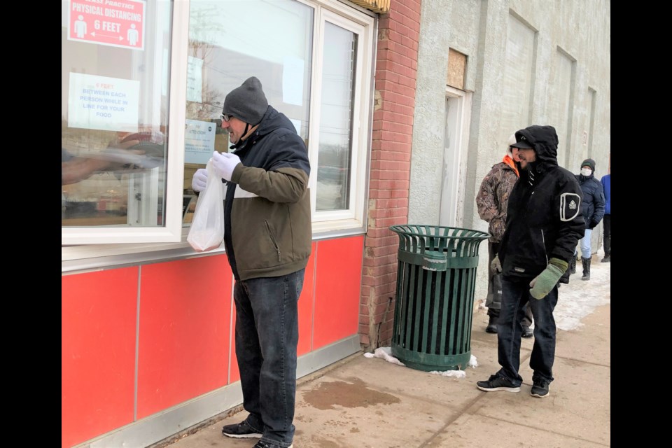 Clients of Riverside Mission pick up their meals through the window of the building. The non-profit organization has started offering lunches again after an eight-month hiatus. Photo by Jason G. Antonio 