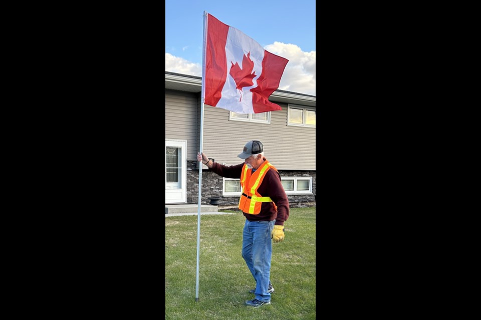 Rotarian David Kettlewell plants a flag in a front yard, as part of the Wakamow Club’s fundraising initiative. Photo submitted  