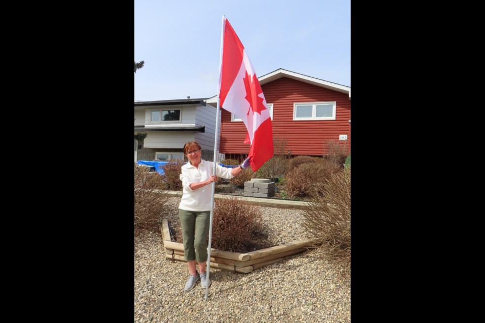 Sonja Susut, with The Rotary Club of Moose Jaw Wakamow, plants a Canadian flag in front of a home. Photo submitted