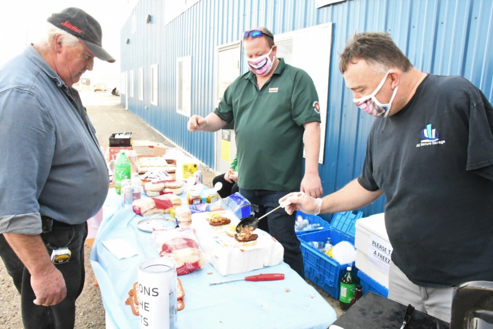 Kent Latimer (right), owner of All Secure Storage, adds onions to Don Firomski's burger, during a barbecue fundraiser on Sept. 21. The event celebrated several company milestones and also helped raise funds for an international Scouting jamboree. Photo by Jason G. Antonio 