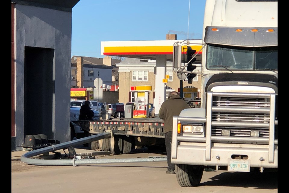 A semi-driver with Walker's Towing observes the damage after the trailer of his semi-truck knocked over the traffic lights at the corner of High Street West and First Avenue Northwest around 1 p.m. on Dec. 18. Photo by Jason G. Antonio 