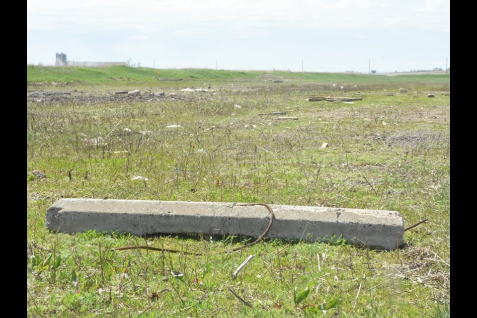 A concrete curb lies in a field that once housed the city's snow dump, along with other debris that contractors picked up while hauling snow this winter. Photo by Jason G. Antonio