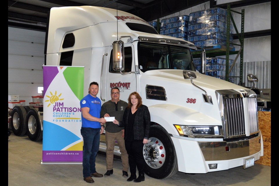 Kayne Hemsing, left, from the Fit II Fight Armsports League and Garett Teriann, owner Rockport Carrier Co. Ltd., present a cheque for $1,500 to Stacie Lawson, manager, development & engagement for the Jim Pattison Children’s Hospital Foundation. (Matthew Gourlie photograph)