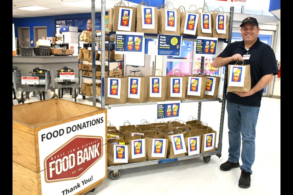Lesslie Ross, manager of Superstore, holds a bag of food that customers can purchase to help support the food bank, as part of the store's annual Holiday Food Drive. Photo by Jason G. Antonio