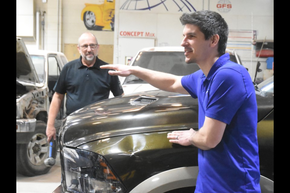 Justin Zelinski (front), with Colour Compass Corporation (CCC) in Edmonton, discusses a dent he made in Terry Beattie's truck that conference participants will practice removing. Photo by Jason G. Antonio 
