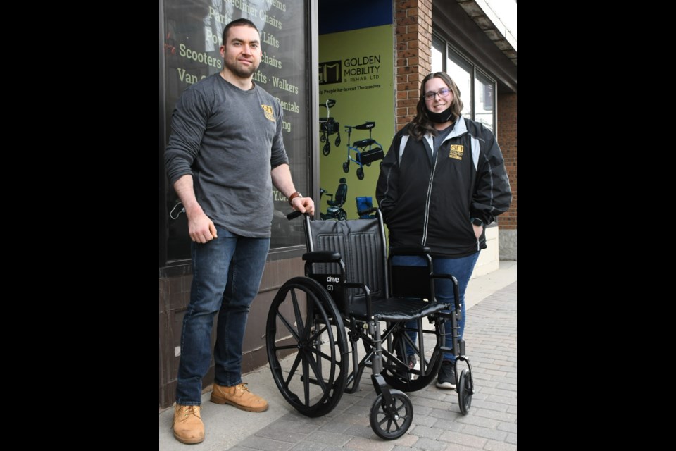 Taylor Mazenc and Brooke Malischewski with Motion/Golden Mobility pose with a wheelchair that the downtown business has donated to the Moose Jaw Curling Club to help it with the 2022 national tourney being held in Moose Jaw. Photo by staff 