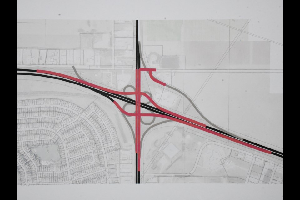 A poster shows the current cloverleaf design of the Highway 2/Main Street North overpass (in grey) and the proposed diamond-shaped changes (in red). Photo by Jason G. Antonio