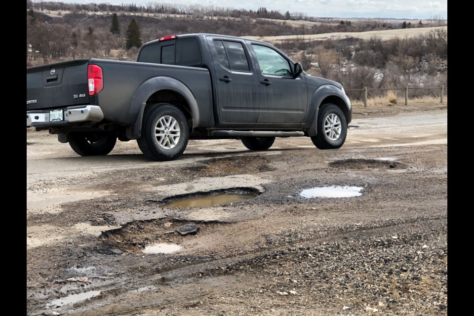 Motorists had to drive slowly around massive potholes on Ninth Avenue Southwest on April 12. Photo by Jason G. Antonio