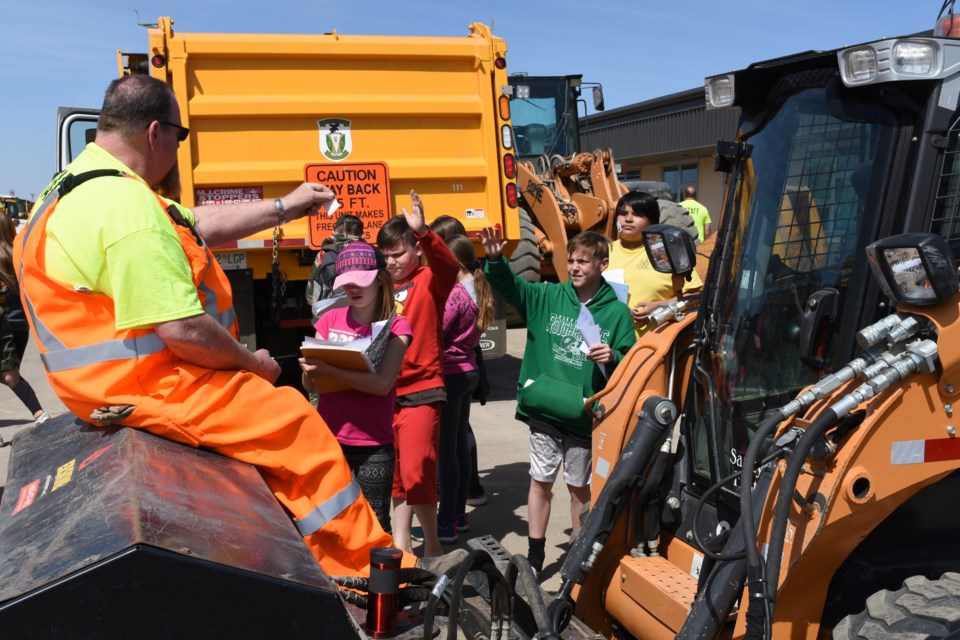 Public works employee Dave Deagle hands out stickers to students from Sacred Heart after they learned more about a bobcat, during an open house at the department’s yard. Photo by Jason G. Antonio 