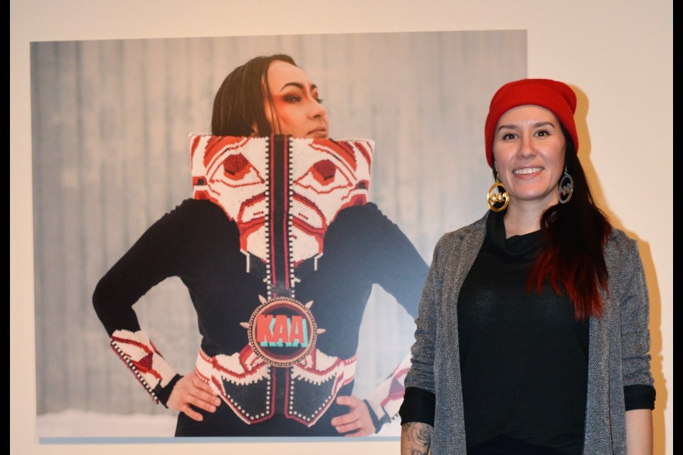 Catherine Blackburn poses beside a picture of her sister wearing a piece of hers based on a design by west coast artist Alano Edzerza. (Matthew Gourlie photograph)