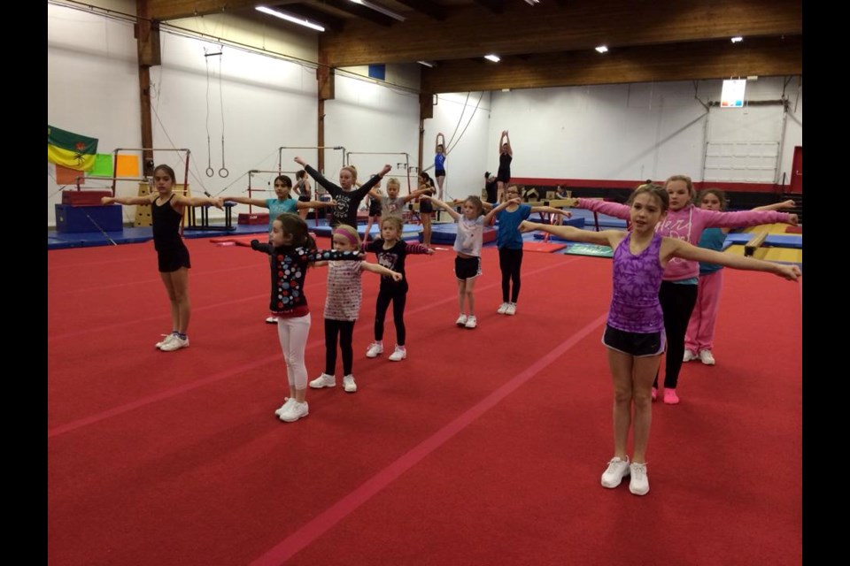 Gymnastics students participate in a warm-up stretch before the start of activities in this Dec. 12, 2013 photo.