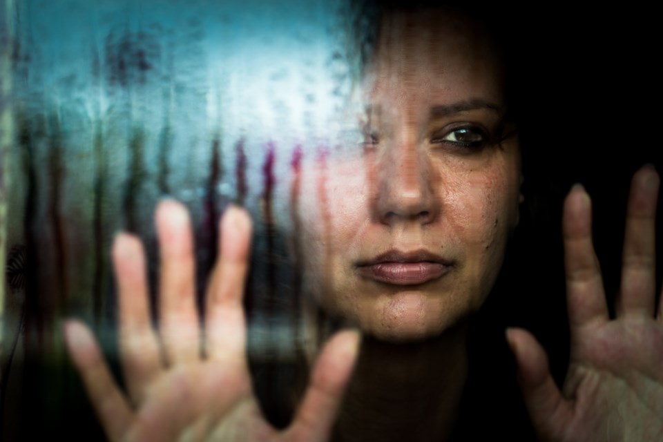 image of frightened woman looking through window