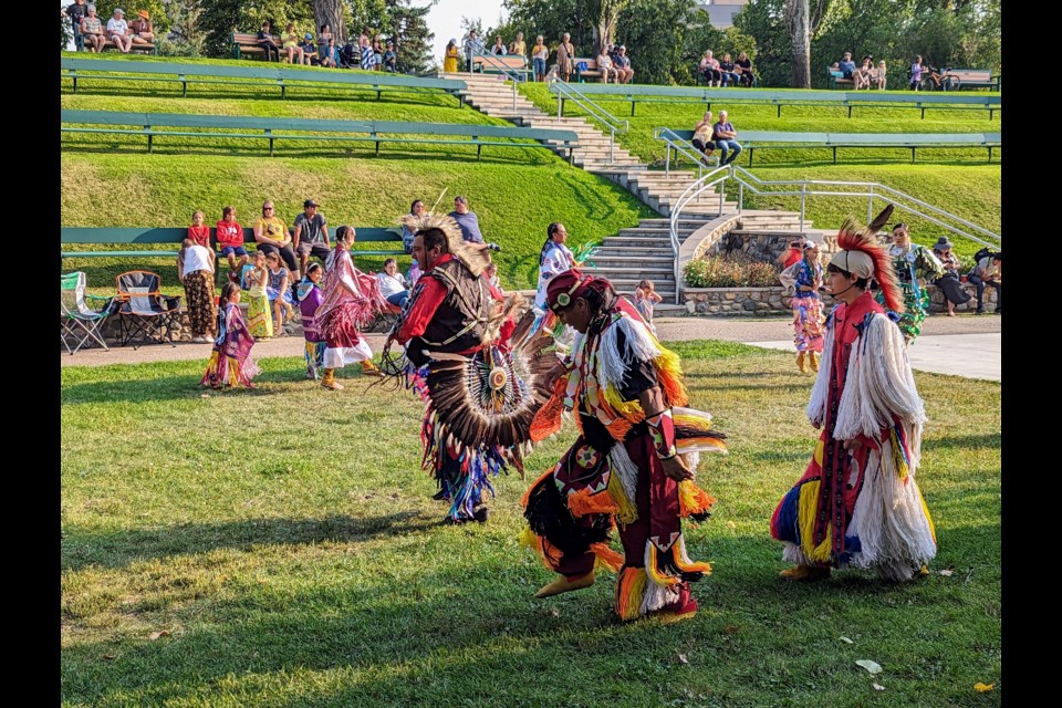 Wayne Fisher is center place in this photo, dancing a traditional warrior's dance. His regalia has a mohawk-style headpiece