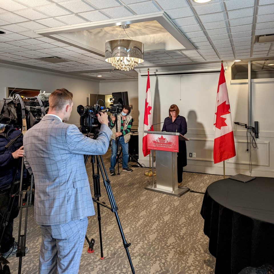 Parliamentary Secretary Marie-France Lalonde announces funding for settlement services in front of a crowd of media at Temple Gardens Hotel